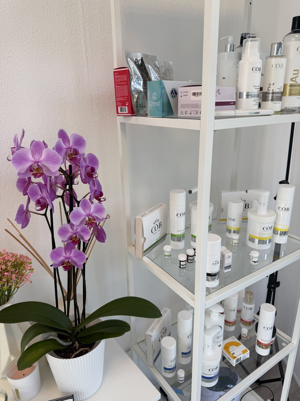 Productplank met huidverzorgingsproducten en een paarse orchidee