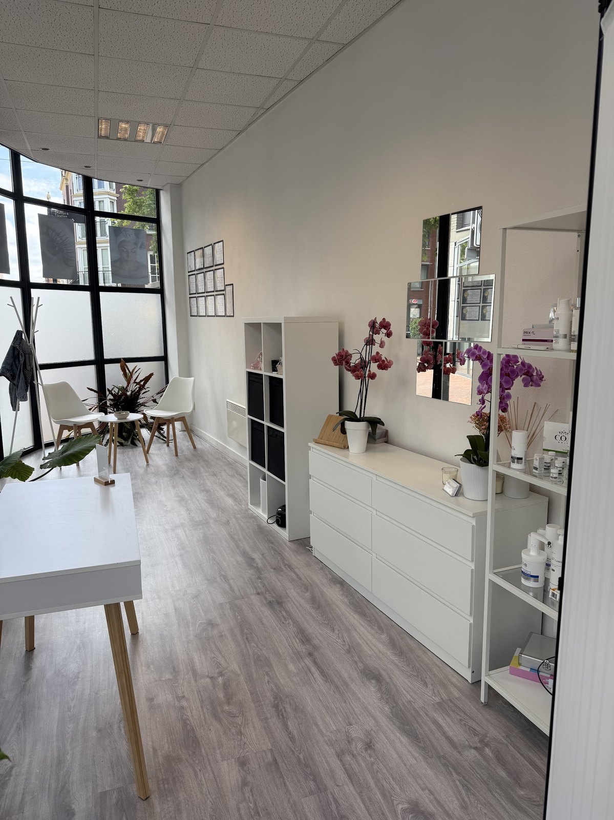 Salon interieur: witte kast met orchideeën, productplanken en spiegeltegels bij het grote raam