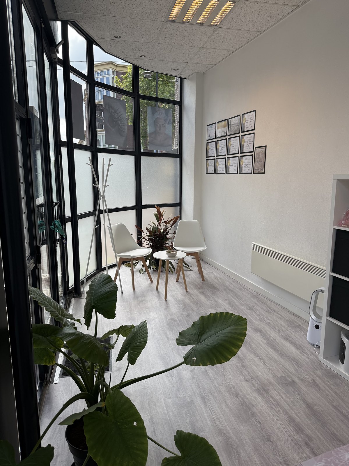 Wachthoek bij het raam met twee witte stoelen, planten en ingelijste certificaten